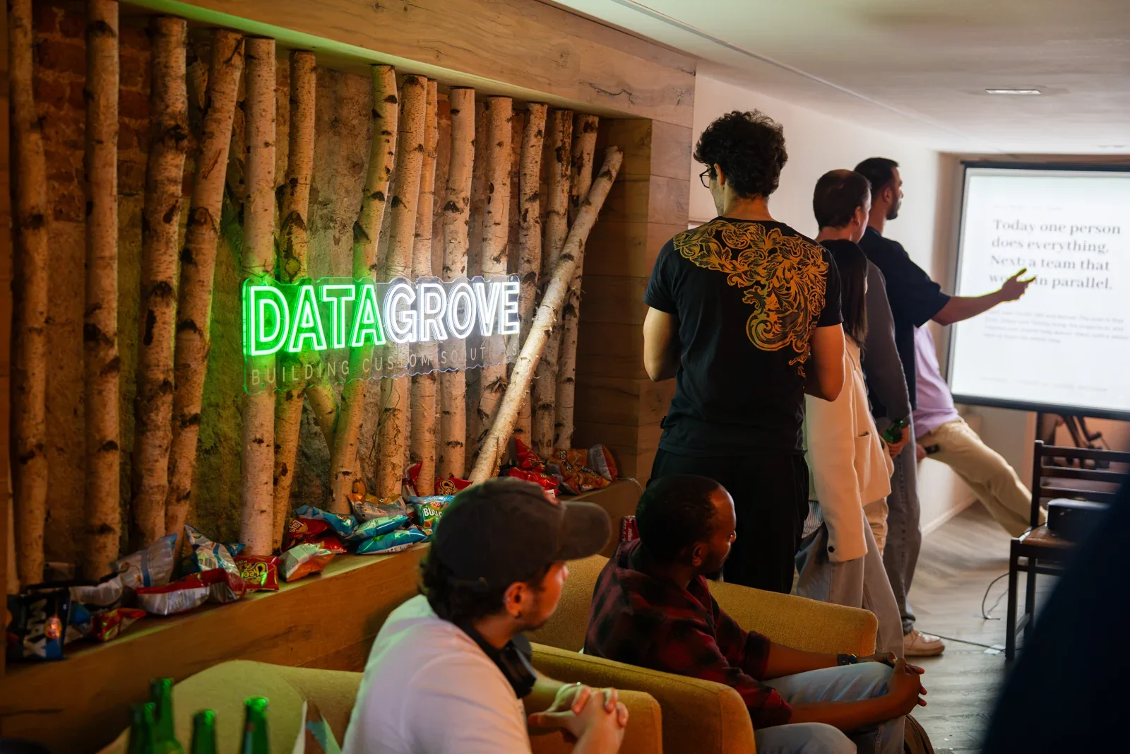 Visitors watching a presentation next to the neon logo